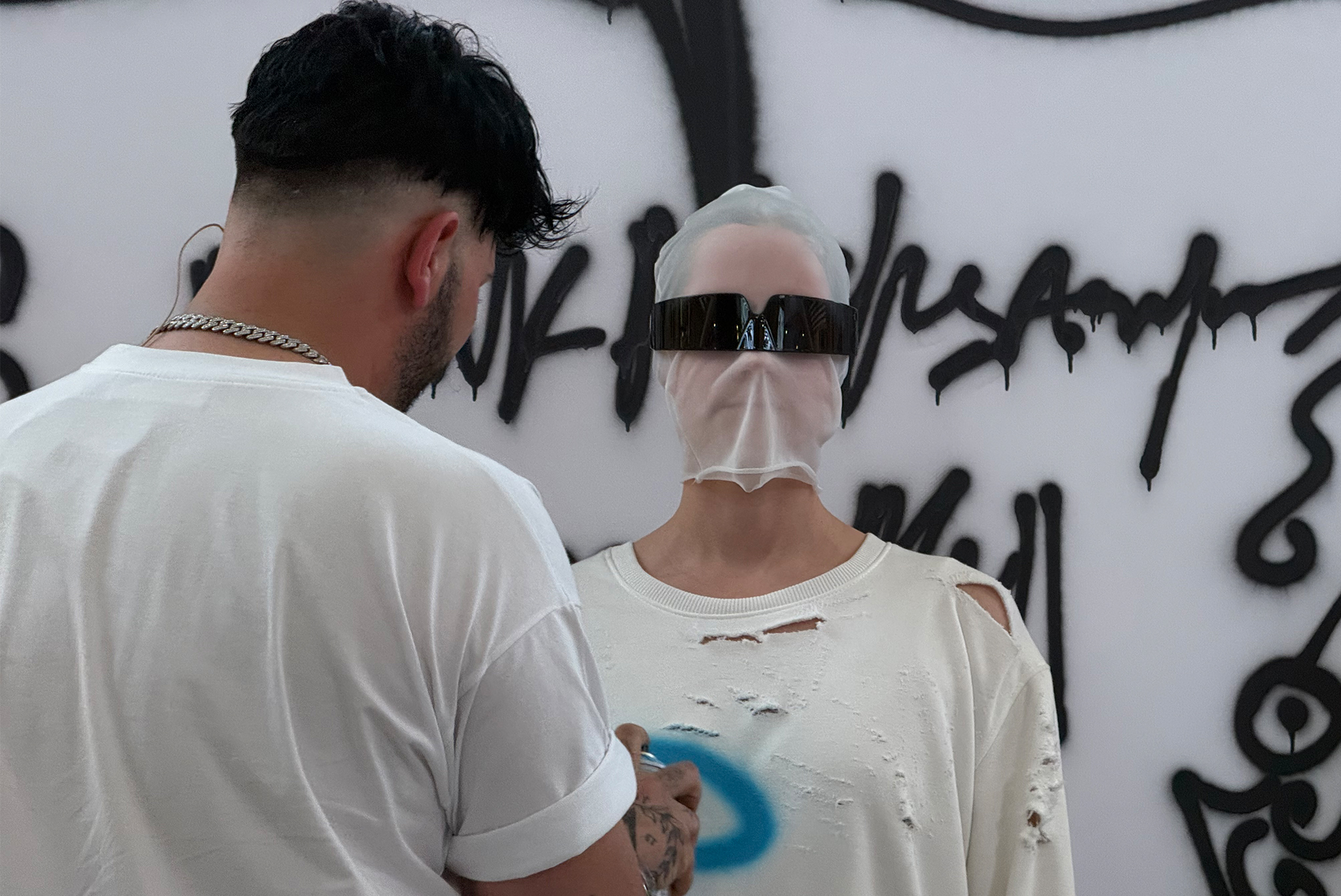 A close-up of a garment as blue spray-painted lines form a face motif during a live fashion performance in Yerevan, Armenia.